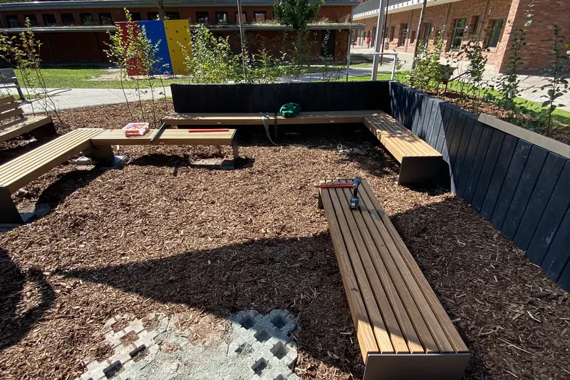 Sitzbänke aus Holz, Rasengitter und Pflanzflächen im Grünen Klassenzimmer