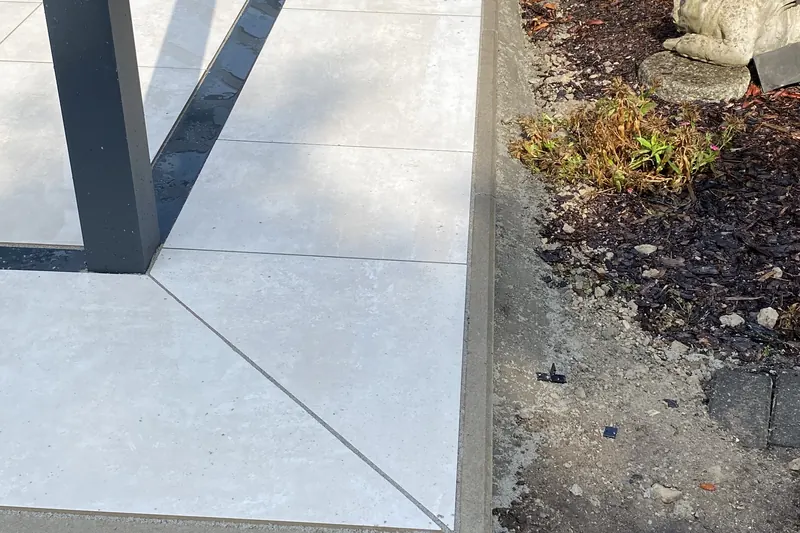 Detail einer Keramikterrasse mit sauber gesetzter Kante zum Beet